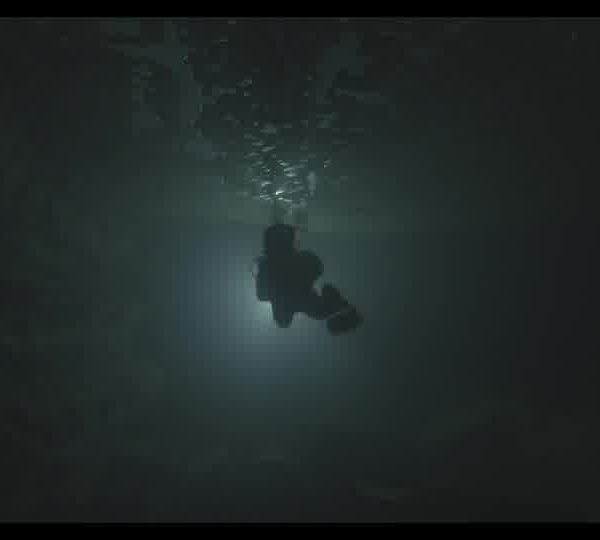 Diver_swimming_front_of_the_light_in_a_dark_underwater_cave_160930SG