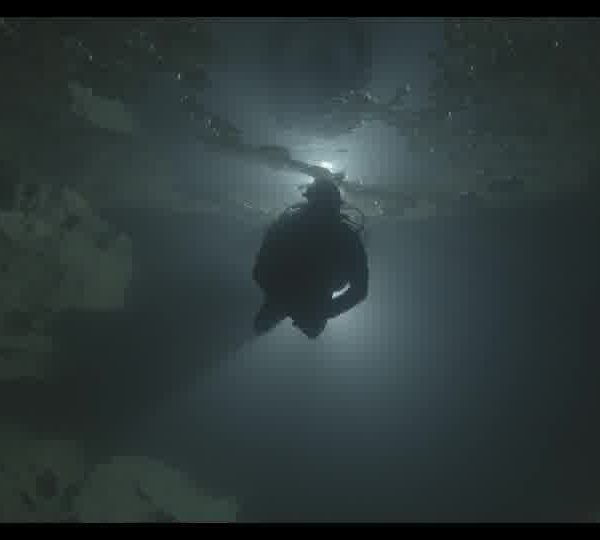 Diver_with_a_flashlight_swimming_in_a_dark_underwater_cave_160930P5